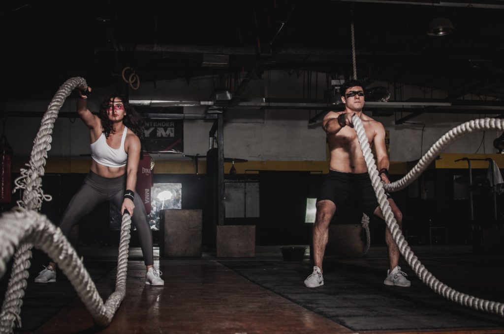 Man and woman exercising with battle ropes