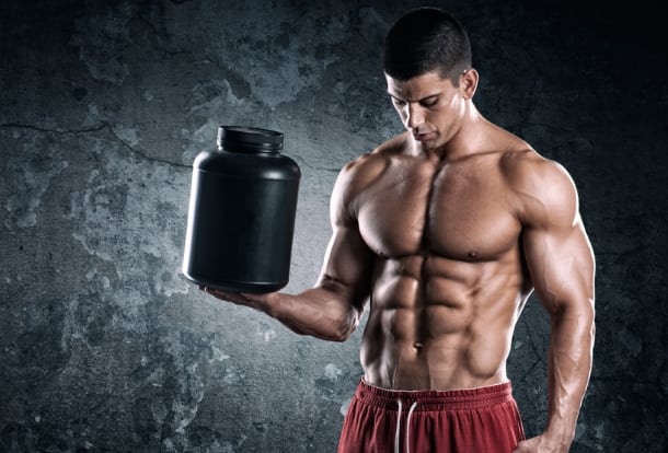 Bodybuilder holding a black dose with supplement